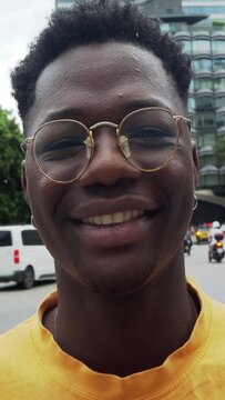Vertical video.Portrait of a young African man with glasses smiling looking at camera. Positive emotions