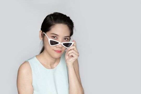 Portrait of Asian beautiful woman peeking over sunglasses with inquisition.
