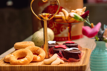 Rosquinhas com sequilhos e doces de chocolate na mesa posta com flores e bolas de natal
