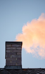 White smoke from a brick chimney in a single-family home. Winter heating season. Heated house with wood.
