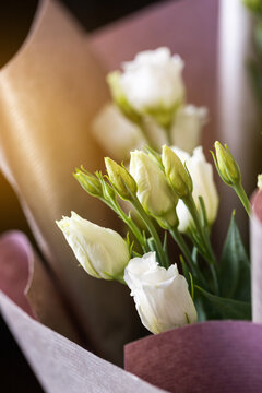 Close Up Of White Eustoma Flowers In A Bouquet Wrapped In Pink Paper.