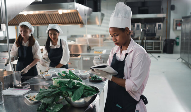 Chef in the kitchen provides cooking training to students.Schoolgirls happily cook together.children wearing cooking uniform.