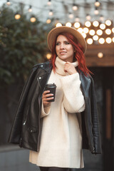 Young creative woman with red hair in cyty street cafe with coffee cup