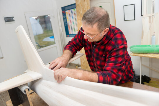 Carpenter and modeler making model of the airplane in his workshop	