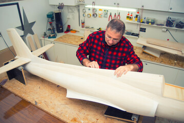Carpenter and modeler making model of the airplane in his workshop	