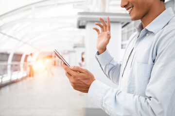 Smiling handsome Asian man vlogger broadcasting from middle of cityscape, Say hello his friends, looking at mobile phone camera, talking, gesturing.