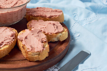 Homemade beef liver pate in a glass jar and baguette slices with pate