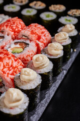 Close up of maki rolls with cream cheese lying on a black flat plate.