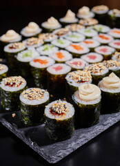 Diverse selection of maki rolls with different fillings on a black board.