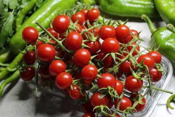 Some tiny cherry tomatoes and green peppers in white plates on wooden concept.