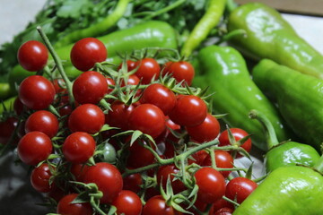 Some tiny cherry tomatoes and green peppers in white plates on wooden concept.