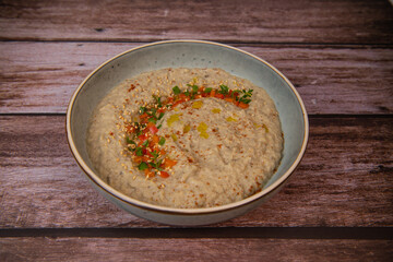 Traditional arabian eggplant dip baba ganoush with herbs and smoked paprika on a wooden background. High quality photo