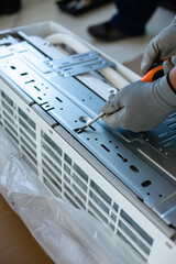Male installation service worker or repairman installs or repairs air conditioner indoors.