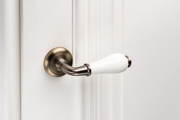 Close up of stylish and elegant door knob or handle on white door.