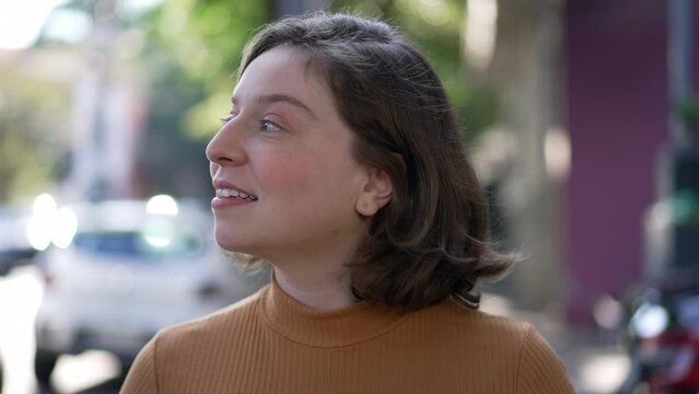 Pensive happy young woman walking in city sidewalk street. Thoughtful person walks forward in contemplation. Mindful person walks outdoors