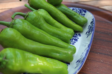 Some tiny cherry tomatoes and green peppers in white plates on wooden concept.