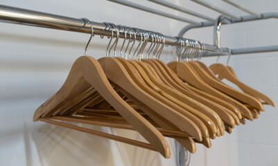 Metal rack with assorted wooden clothes hangers on white background - Powered by Adobe