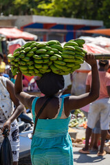 Haitian lady carrying a bunch of green plantains on her head in the Haitan Market of pedernales,...