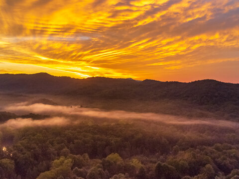 Gorgeous sunrise over the Appalachian mountain with fog surrounding it below and an orange sky