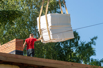 styrofoam panels are lifted to the roof of the building with a crane