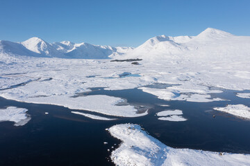 Beautiful aerial drone Winter landscape images of Loch Ba and snow covered mountains in background...