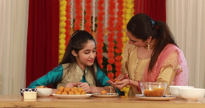 Mother teaching her daughter how to make ladoos on Diwali