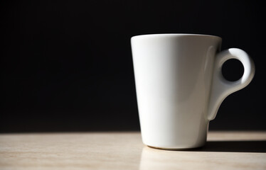Obraz premium A white mug with coffee stands on a table against a dark gray background.