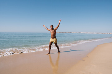 Fototapeta na wymiar GUY WALKING ON THE BEACH ON HIS SUNNY VACATION VERY HAPPY