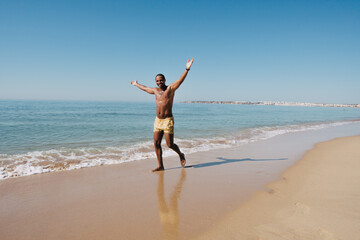 GUY WALKING ON THE BEACH ON HIS SUNNY VACATION VERY HAPPY