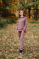 Young woman in hoodie sweater in an autumn park. Sunny weather. Fall season.