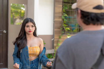 A beautiful teenager in a denim outfit and loose curls gestures her hands as she tries to explain her frustrations to her dad. - obrazy, fototapety, plakaty