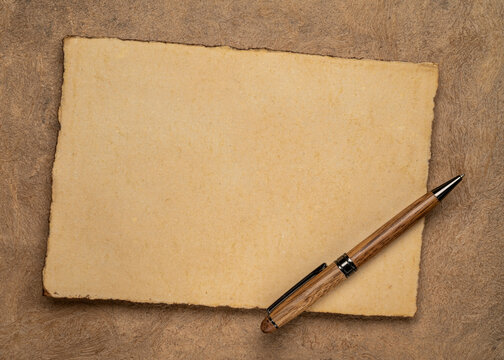 sheets of blank handmade paper with rough edges and a stylish pen against textured bark paper