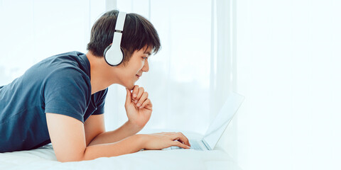 Happy man using Laptop computer and checking good News in the Bedroom. COPY SPACE. Trading. Watching Movie. WORK FROM HOME Concept.