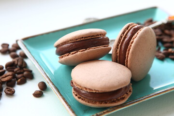 Dessert with coffee. Coffee chocolate macaroons on a plate with coffee beans. Sweet present, cafe menu. Sweets still life.