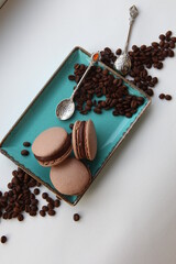 Dessert with coffee. Coffee chocolate macaroons on a plate with coffee beans. Sweet present, cafe menu. Sweets still life.