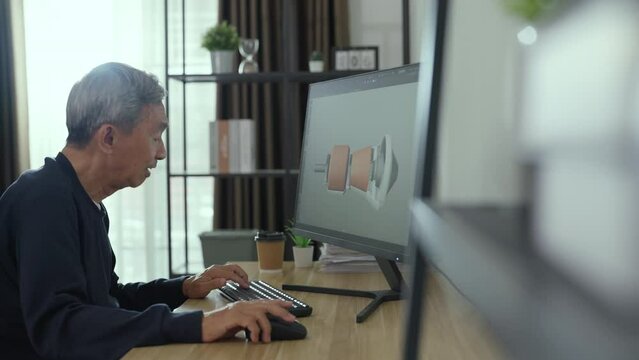 Senior asian man developer work at his studio. He using computer to design machine parts at his work place. Technology and Development concept.