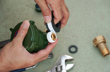 Plumber puts a sealing tape on the thread of the water valve.