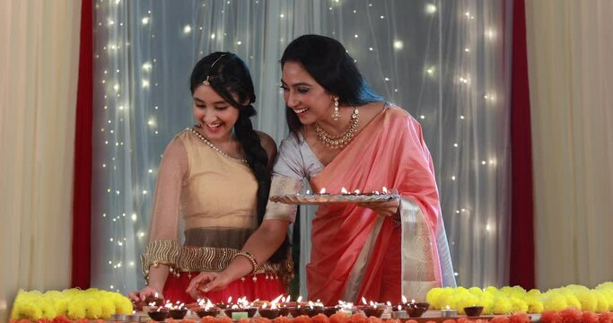 Mother and daughter decorating house with diyas on the occasion of Diwali