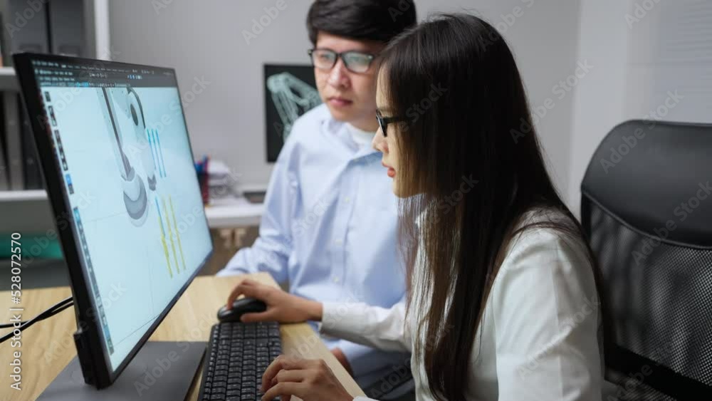 Wall mural asian developer using 3d program to design robot arm. they are trying to develop robot arm together.