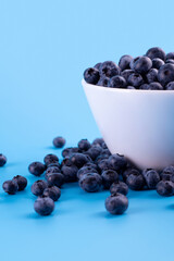 Beautiful fresh blueberries in a white bowl on a blue background.Vegan and vegetarian concept. Summer healthy food.