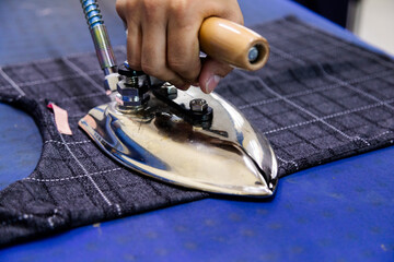 Tailor ironing clothes in tailoring shop