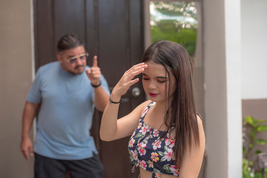 A teenage girl covers her face as she feels shy being scolded by her father early in the morning.