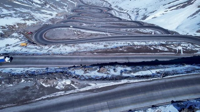 Famous winding road at Andes Mountains. Los Caracoles highway road near Santiago Chile. Snowing scenery. Snow highway road. Winding curves background near Argentina and Chile border.