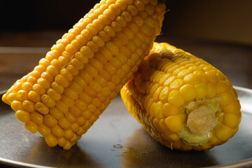 Close view on Homemade sweet corn cobs with salt in bowl on  wooden table