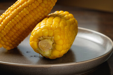 Close view on Homemade sweet corn cobs with salt in bowl on  wooden table