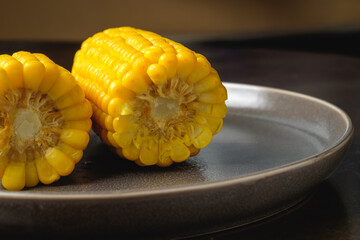 Close view on Homemade sweet corn cobs with salt in bowl on  wooden table