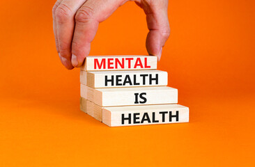 Mental health psychological symbol. Concept words Mental health is health on wooden blocks on a beautiful orange table orange background. Psychologist hand. Psychological mental health concept.