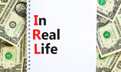 IRL in real life symbol. Concept words IRL in real life on white note on a beautiful background from dollar bills. Business and IRL in real life concept. Copy space.
