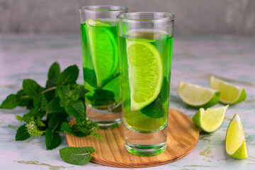 Mint alcoholic liquor with lime in shot glasses.
