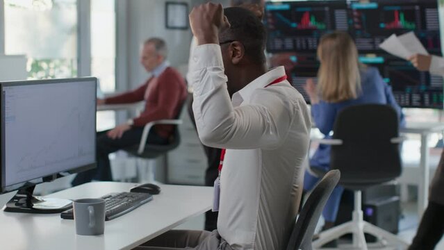 Side view of African American trader look at computer screen and do winner gesture